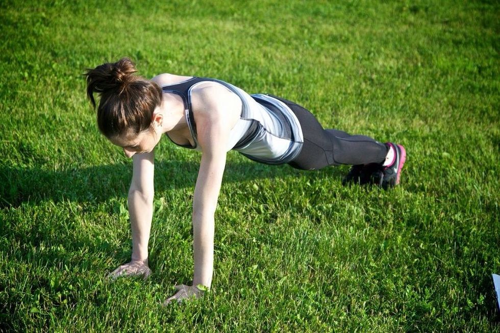 PLANK JACKS: Get into plank position with arms directly under your shoulders and a straight back.