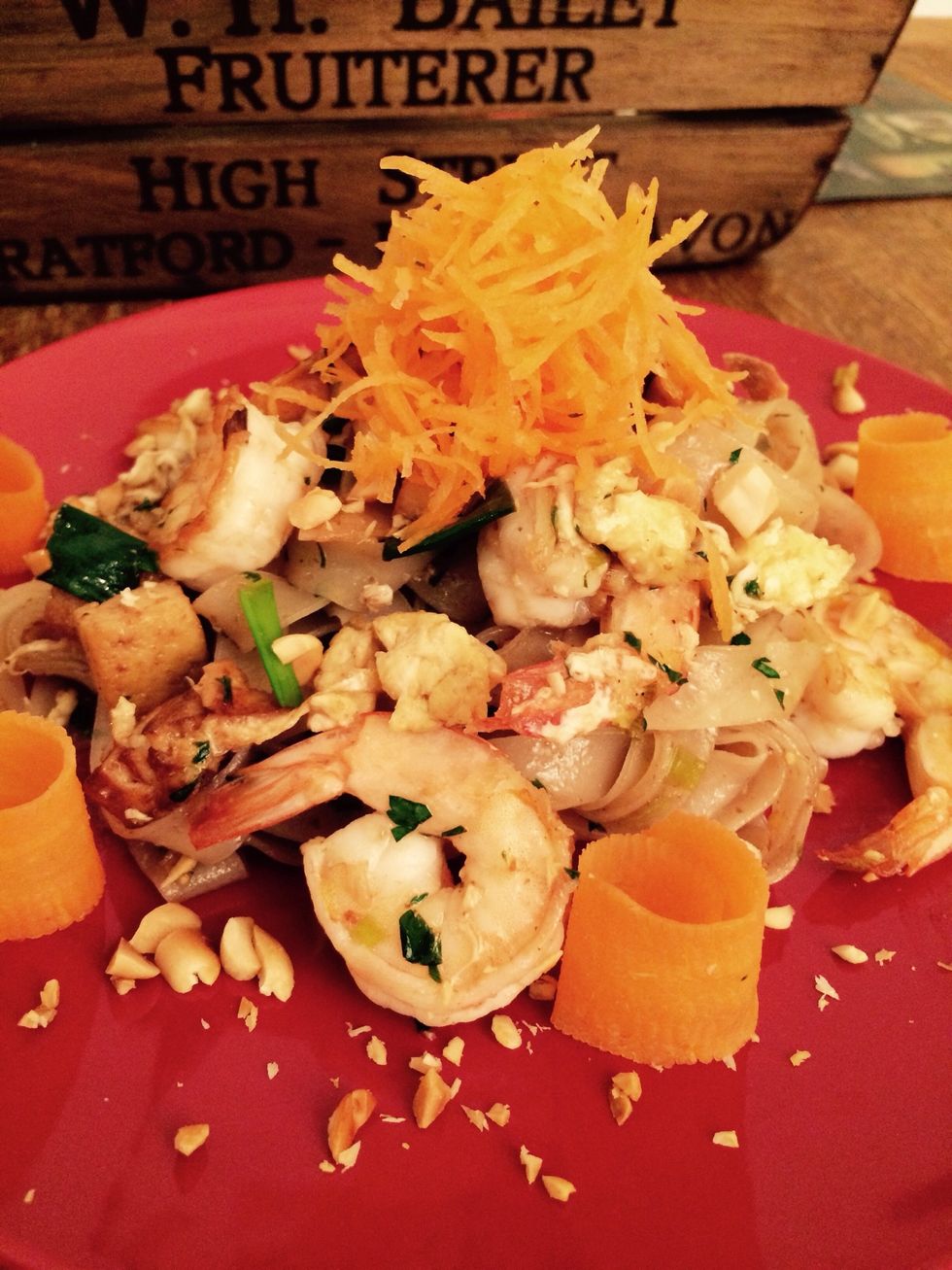 Plate the pad thai and garnish with the remaining peanuts, the carrots and the wedge of lime.