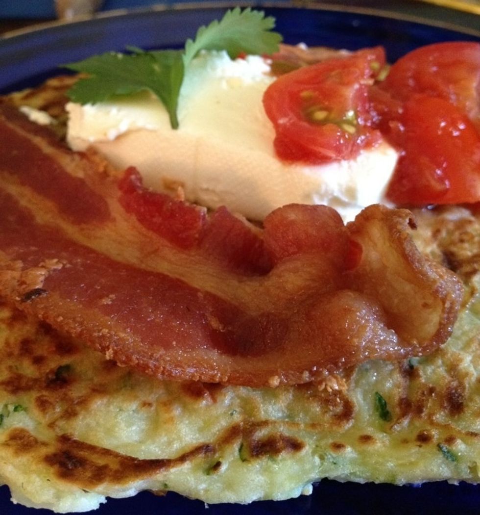Plate your pancake and re-warm it in the microwave until steamy. Garnish with cream cheese, a spoon full of salsa with sliced cherry tomatoes, cilantro and a strip of bacon.