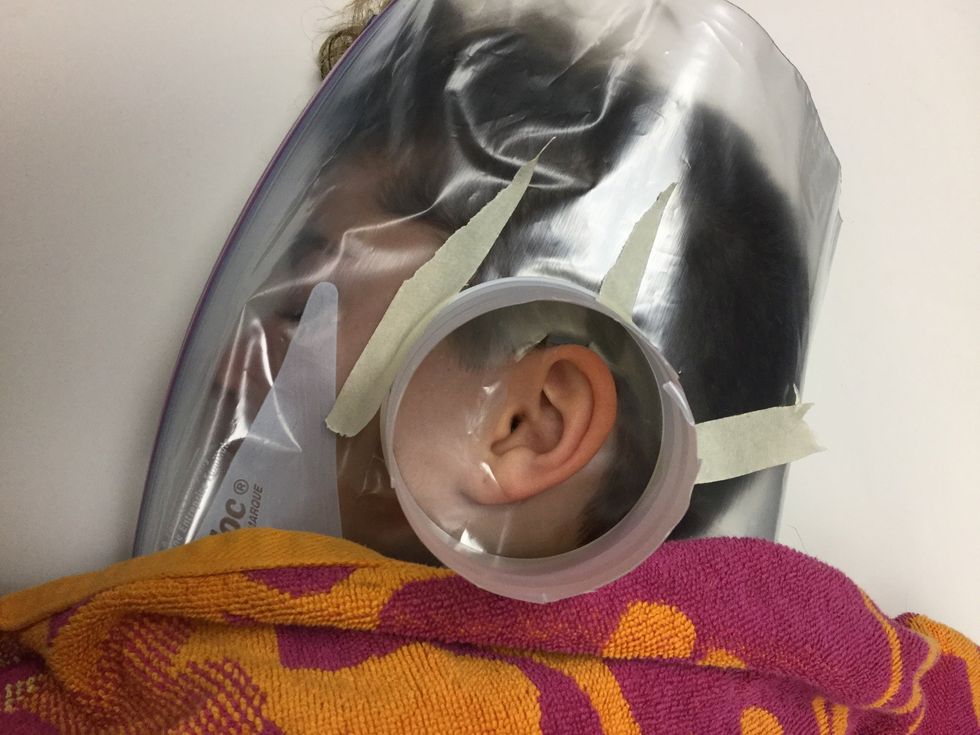 Play's cup on top of your friend and tape it there(be careful not to Trap any hair underneath)