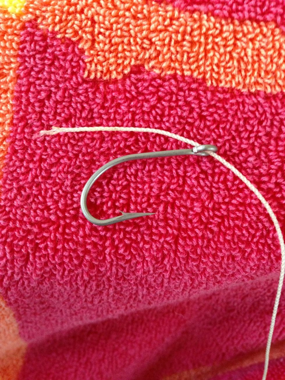 Poke the fishing line through the hole as shown. It is essential to poke it in the front so the hook is facing upward when done. This is so you can hook the fish easier.