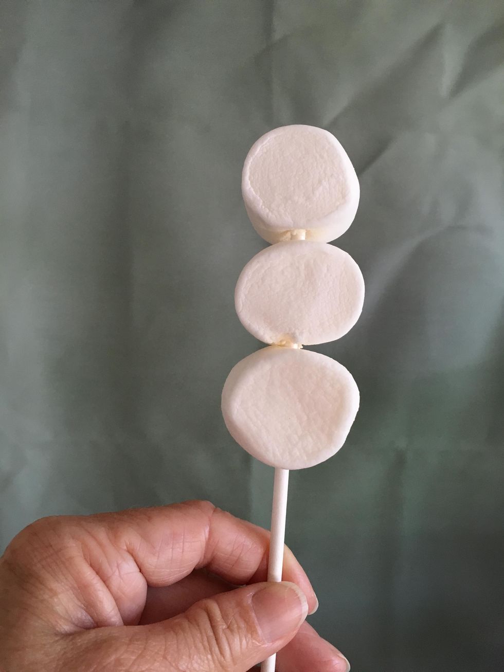Poke the lollipop stick through the three marshmallows. I kept the rounder side to use and the face of the snowman.