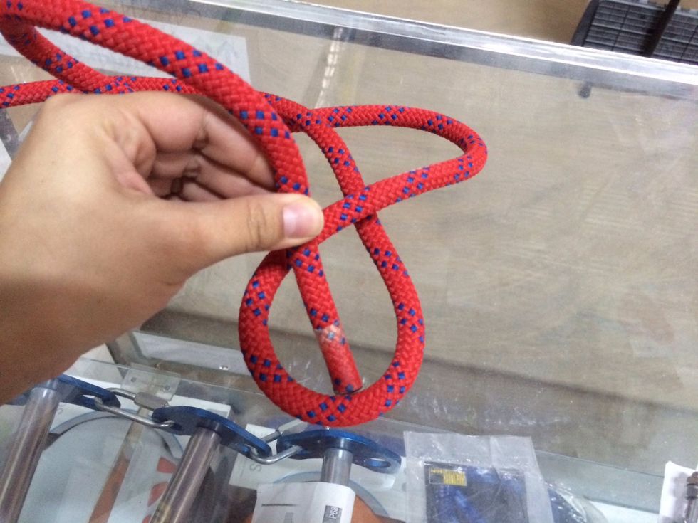 Poke the short side (tag end) of the rope away from you through the bottom hole.