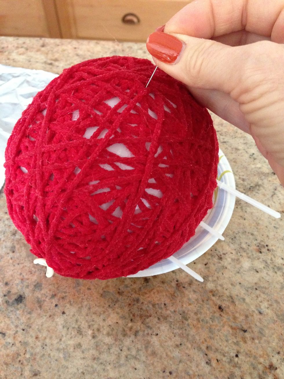 Pop balloon. Air will slowly seep out separating the balloon from the yarn ball