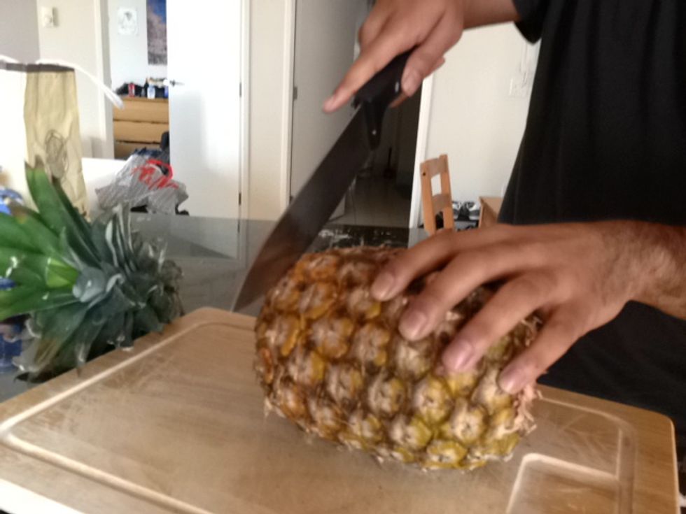 Position knife on bottom of pineapple.
