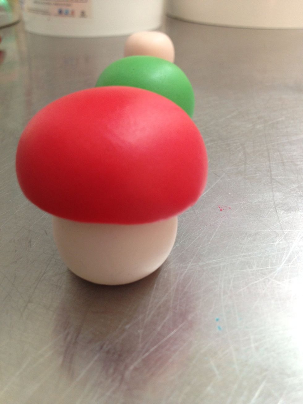 Posizioniamo un mezzo stuzzicadenti all'interno della pasta rosa e ci andiamo ad adagiare e poi incastrare la cupoleta rossa