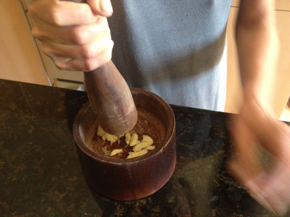 Pound the garlic with a pestle until it reaches the consistency of shaved coconut (see next step).   TIP: add a little salt to prevent the garlic from splashing.