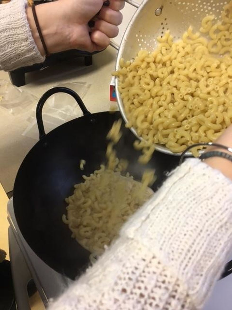 Pour 1/4 of the cheese sauce into a wok and add the strained macaroni.