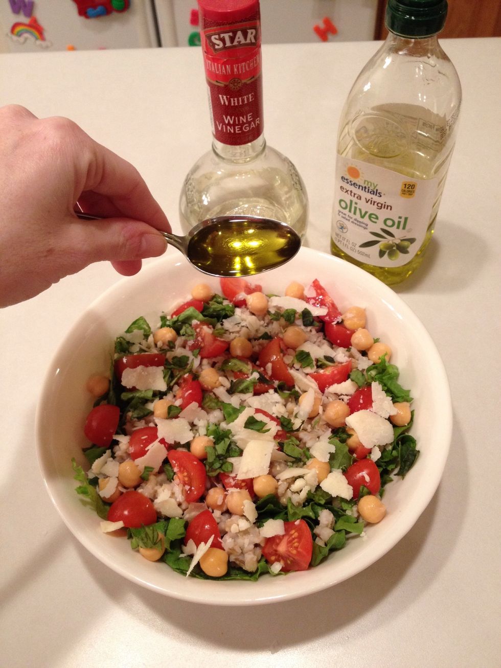 Pour 1 spoonful oil over salad.  Repeat with vinegar.
