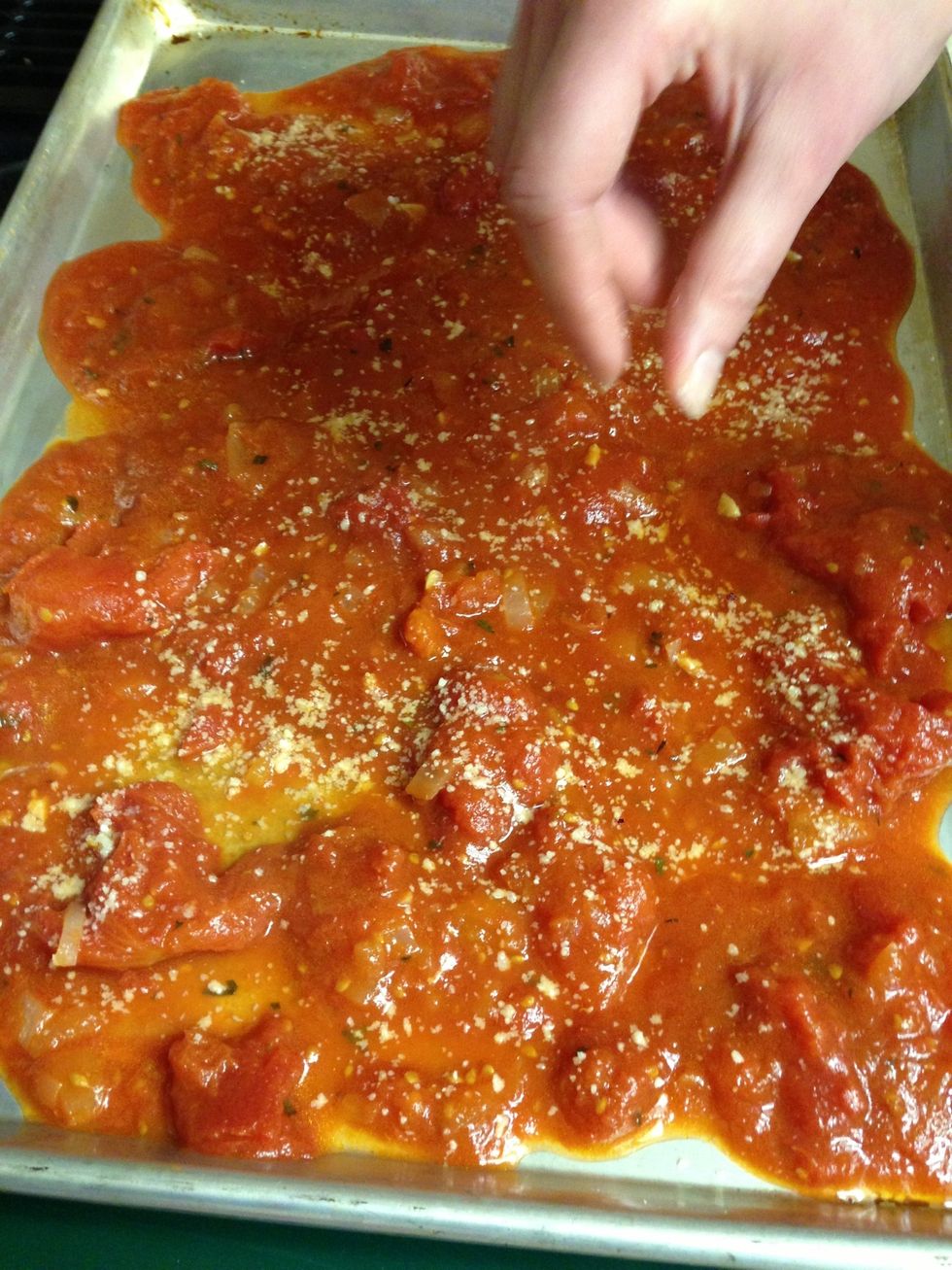 Pour a layer of marinara on a baking sheet and sprinkle Parmesan on top