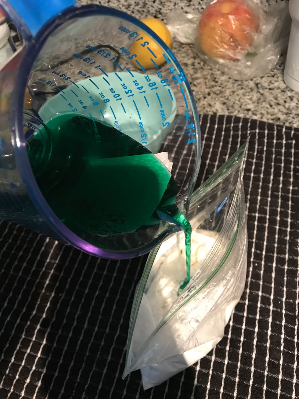 Pour a small portion of the water and food coloring mixture (about 1/2 or 1/4 of the bowl) into the ziplock bag with the cornstarch.