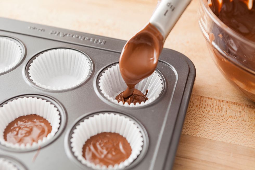 Pour about 1\u00bd tsp of melted chocolate into each muffin cup.