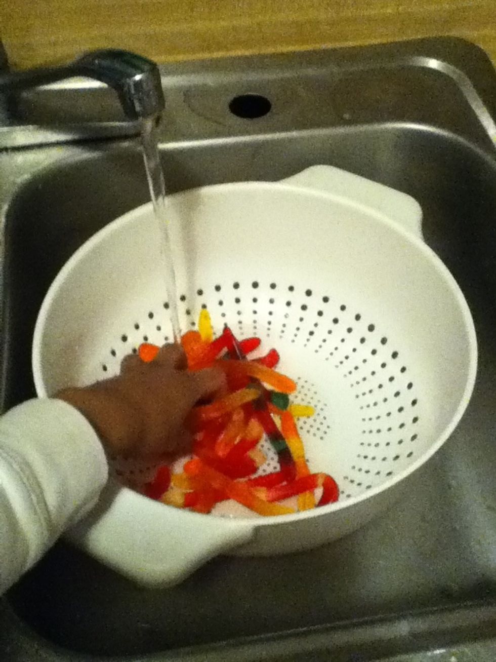Pour all gummy worms in the bowl with holes then start to wash the gummy worms  with cold water for only about one minute