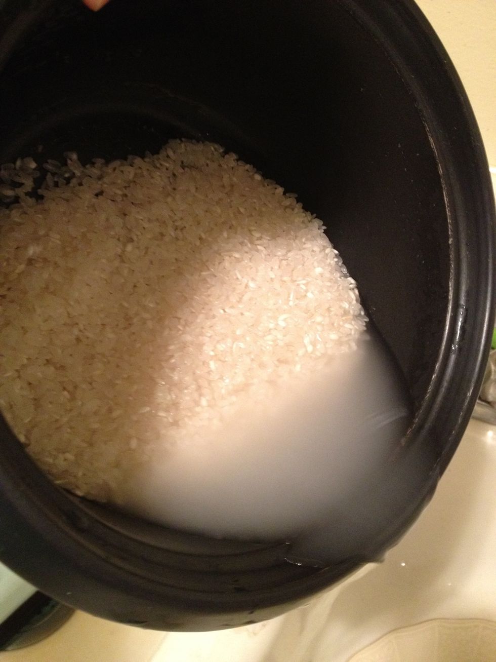 Pour dry rice into the pot. Rinse by filling up with warm water, swishing the rice around with your hand, then pouring out the water. Repeat until water is no longer cloudy.