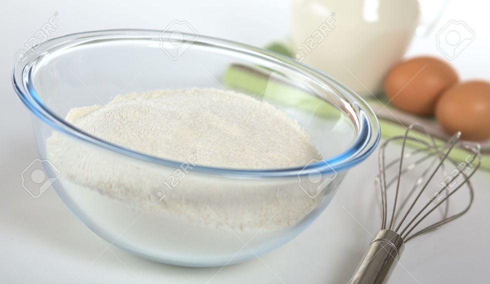 Pour four cups of milk into your metal bowl and squirt a little bit of mustard in there too, then whisk them together. Then pour four cups of flour into your ziplock bag and add your seasoning