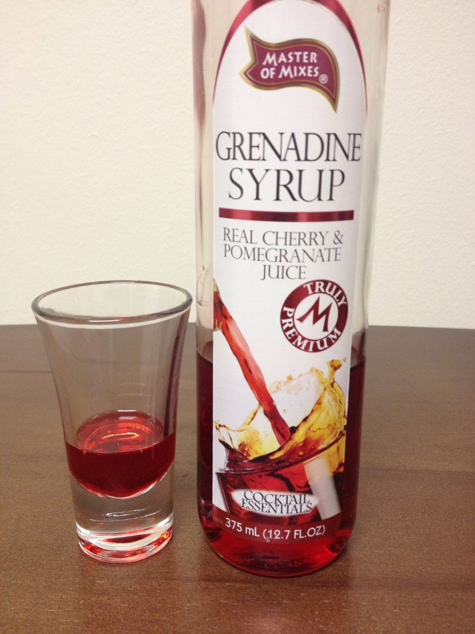 Pour in an ounce of Grenadine into the shot glass.
