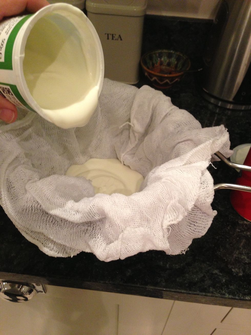 Pour in yoghurt (both pots), using spoon to get all yoghurt out the pot.