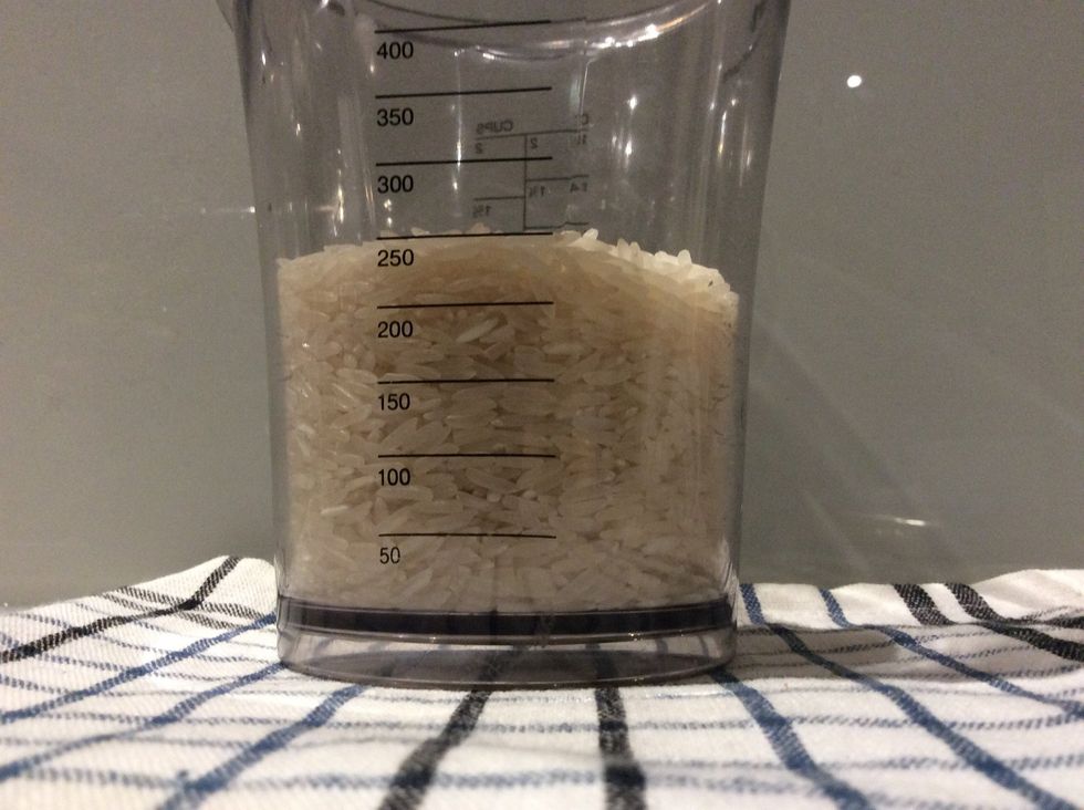 Pour in your rice into your measuring cup at 250 ml, then pour it into your saucepan>>>>