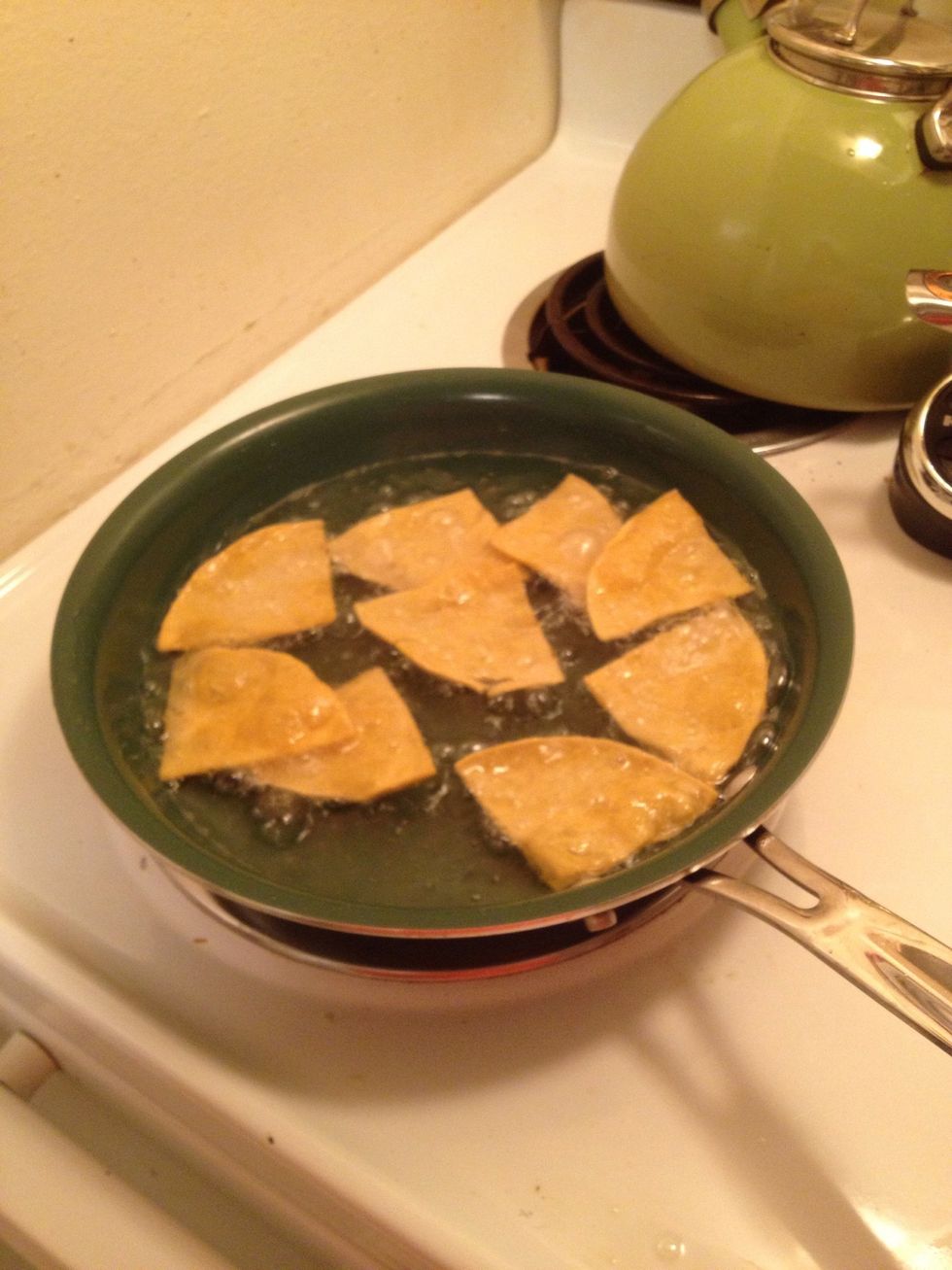 Pour oil in pan, put the burner on 7. Add a stack of tortilla quarters to the skillet like this.