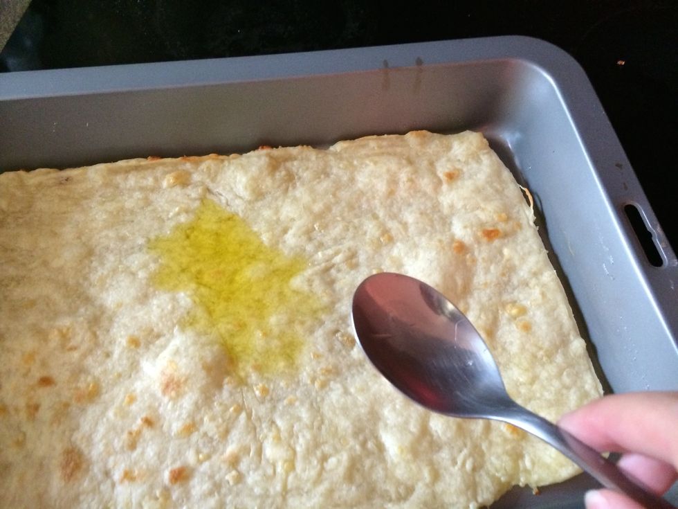 Pour oil onto the pizza base and spread around.