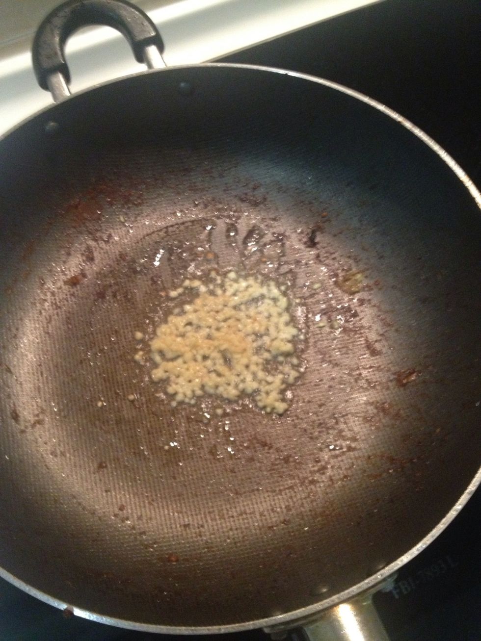 Pour some cooking oil into a pan and add some chopped garlic in.
