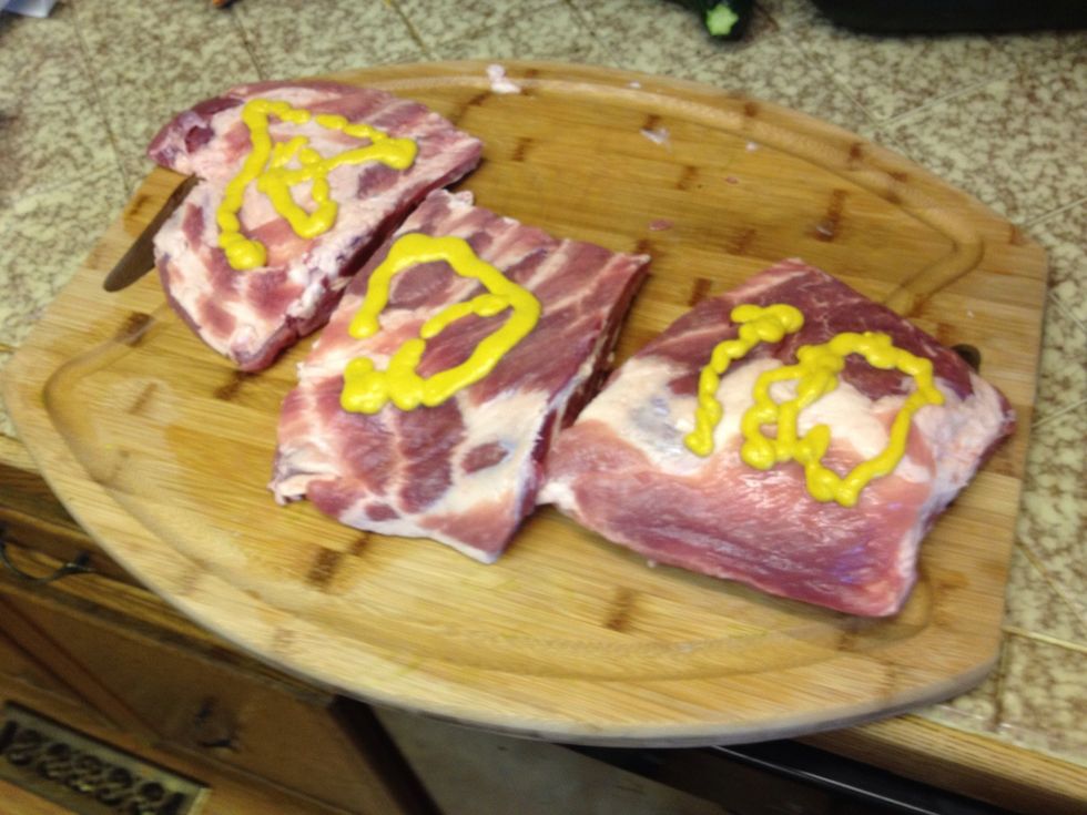 Pour some mustard on the outside of the ribs. This doesn't add flavor, but allows the dry rub to stick to the ribs throughout the smoking process.