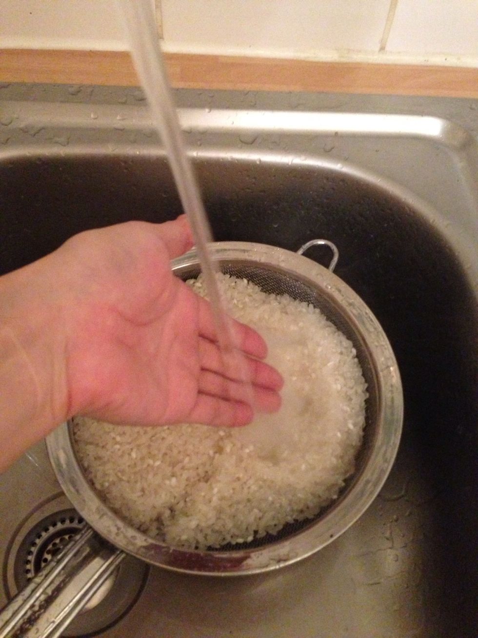 Pour some water enough to cover the rice. Put your hand over the rice to prevent the strong tap water hit rice directly - the rice may crack with water otherwise.