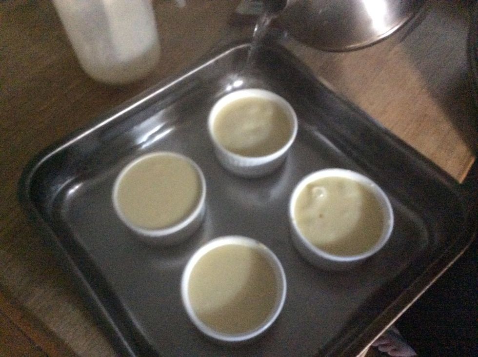 Pour the boiling water into tray until it submerges three quarters of the ramekins