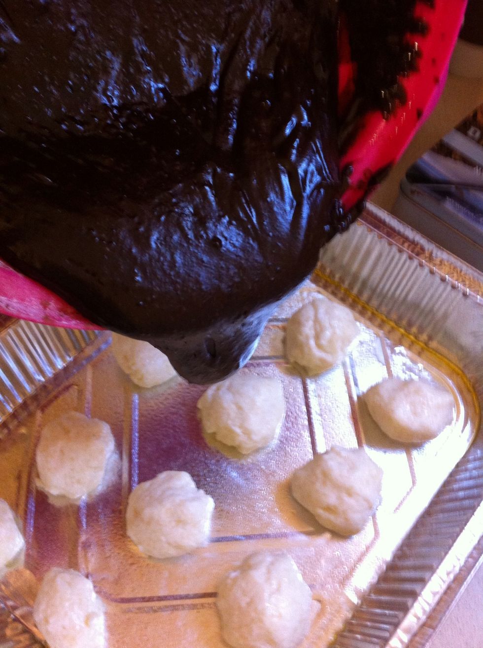 Pour the brownie mixture over cheese and coconut balls.