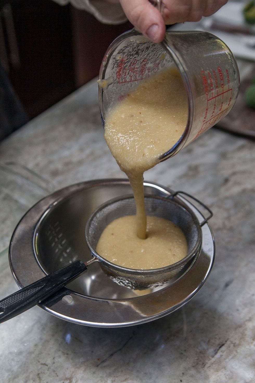 Pour the guava puree through a sieve and into a bowl to remove all the little seeds.