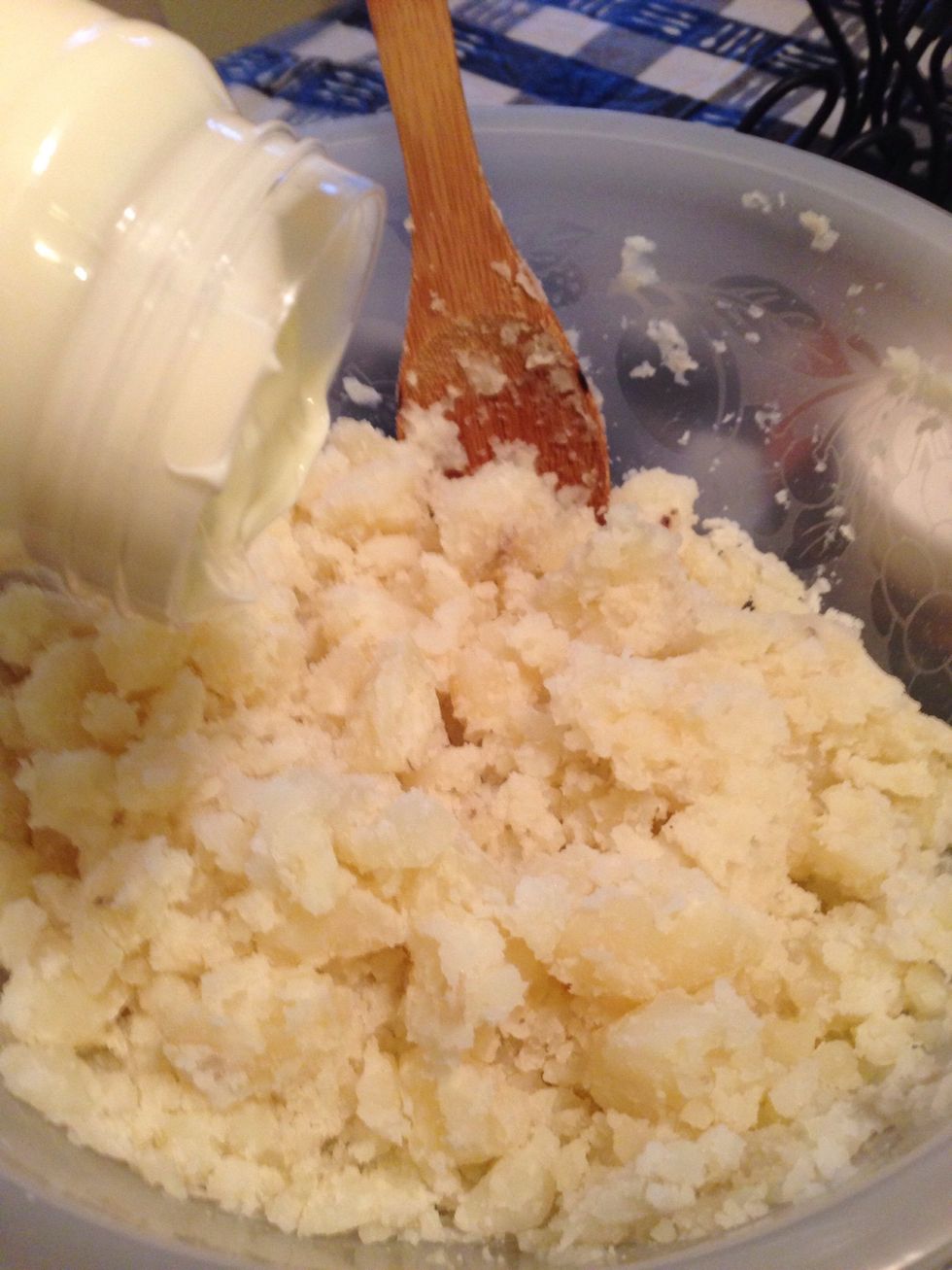 Pour the mayonnaise into the bowl of potatoes.