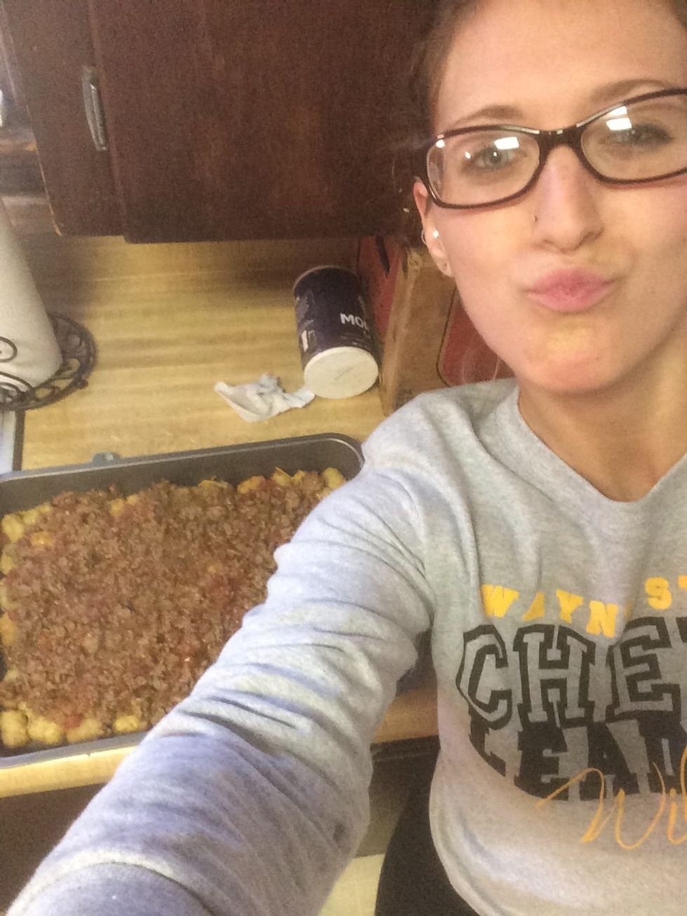 Pour the meat mixture on top of the tator tots you pulled out of the oven. Drizzle 2 tablespoons of taco sauce on top. Then sprinkle a light coat of cheese to cover the top.