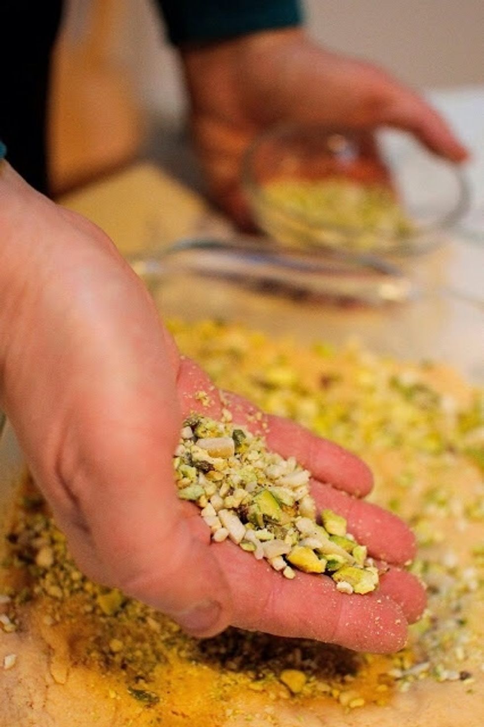 Pour the mixture into a lightly buttered square pan. Press it down well and flatten it. Sprinkle the top with the ground pistachios and almonds. Press them in well.