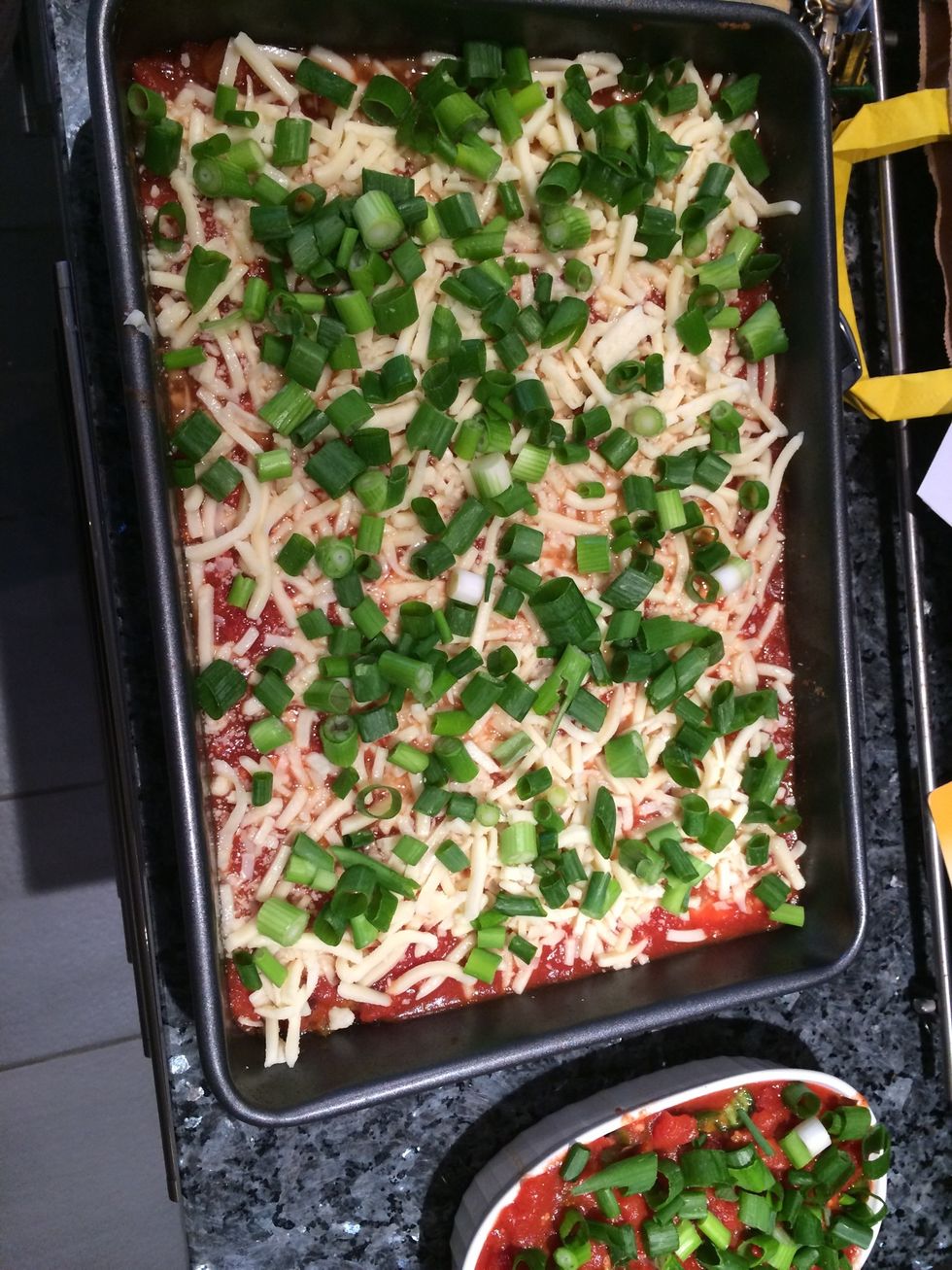 Pour the sauce over the enchilada wraps. After sprinkle some grated mozzarella cheese on top and add chopped spring onions. Now ready to bake until cheese is golden brown.