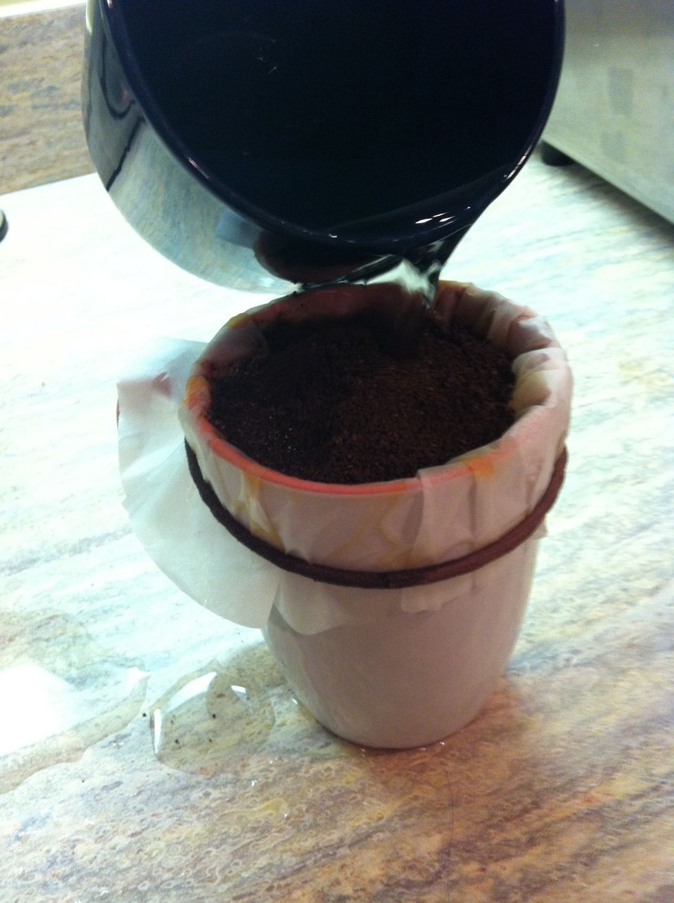 Pour the water on top of the coffee grounds