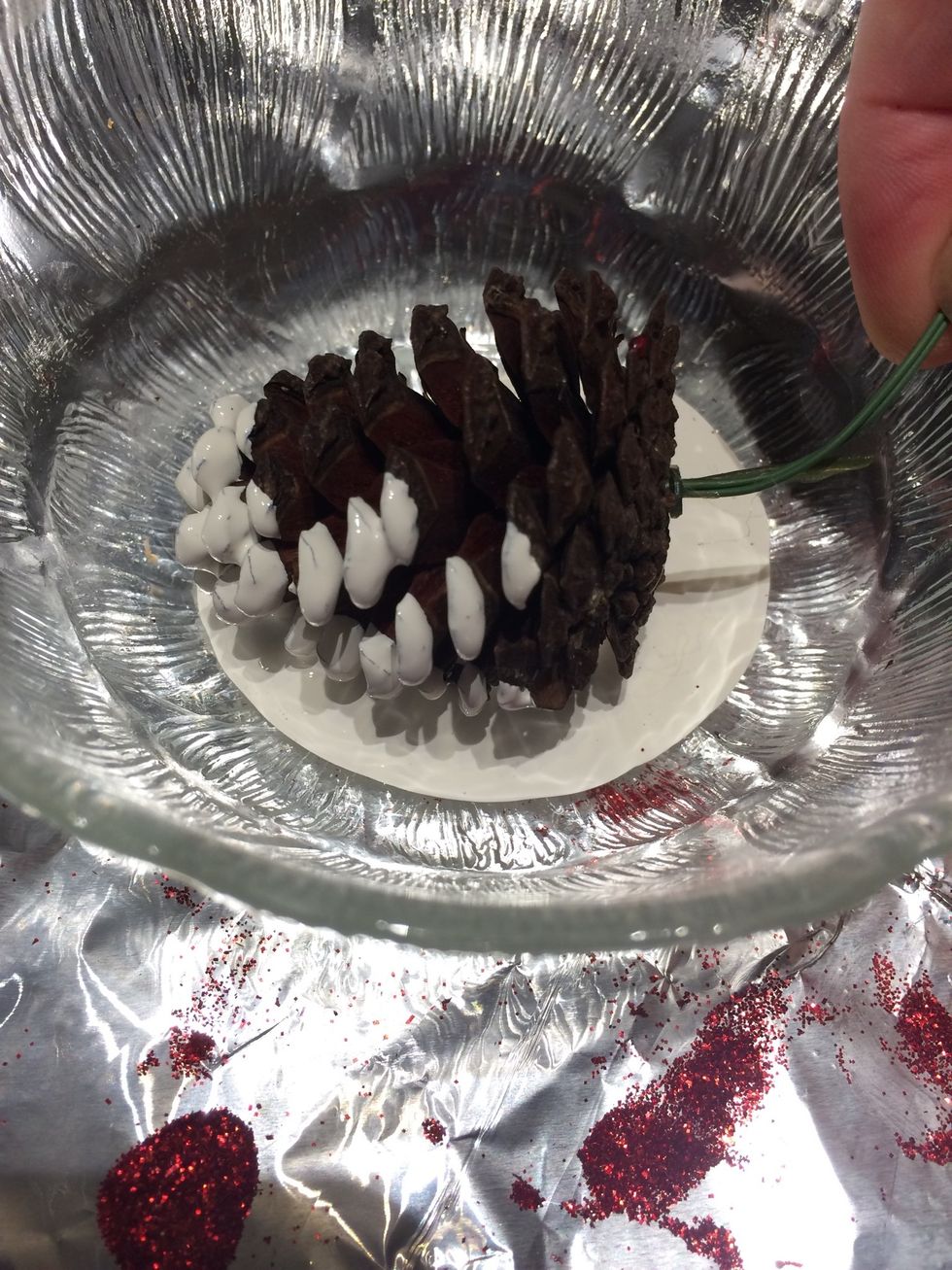 Pour the white acrylic paint into a bowl. You can either roll the pine cone in the paint or apply the paint with a brush. I prefer using a brush.