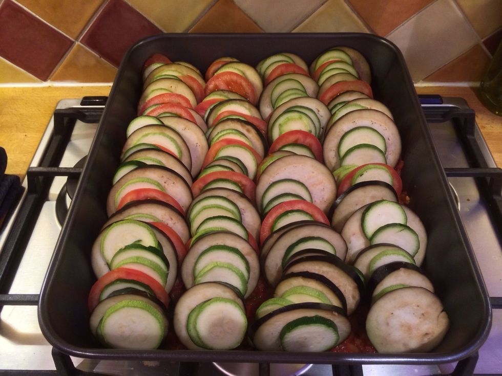 Pour your onion and tomato sauce into the bottom of a large baking tray and layer your veg on top of the sauce like so.
