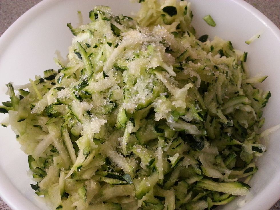 Preheat oven to 170C. Grease a 20cm cake tin/ baking dish. Combine grated zucchini and salt.