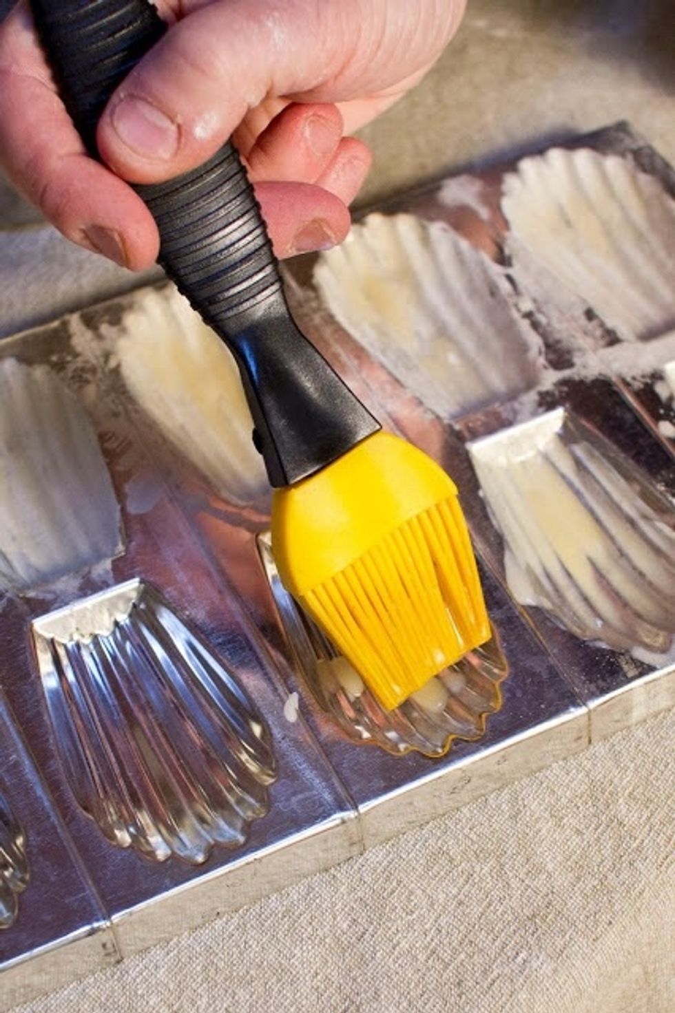 Preheat the oven to 375 degrees.bTake a pastry brush and brush the mold in the madeleine pan. Make sure every ridge and corner is coated.