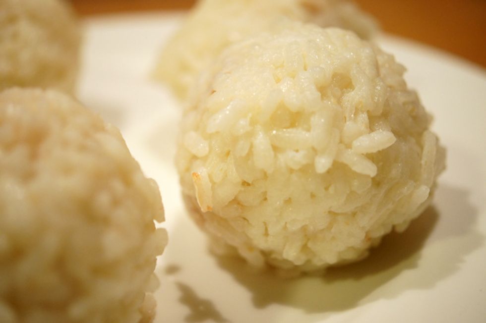 Prenez une poign\u00e9e de riz et formez une boulette avec un trou au milieu et mettez une cuill\u00e8re \u00e0 caf\u00e9 de farce et un peu de mozzarella. Fermez la boule avec un peu de riz .