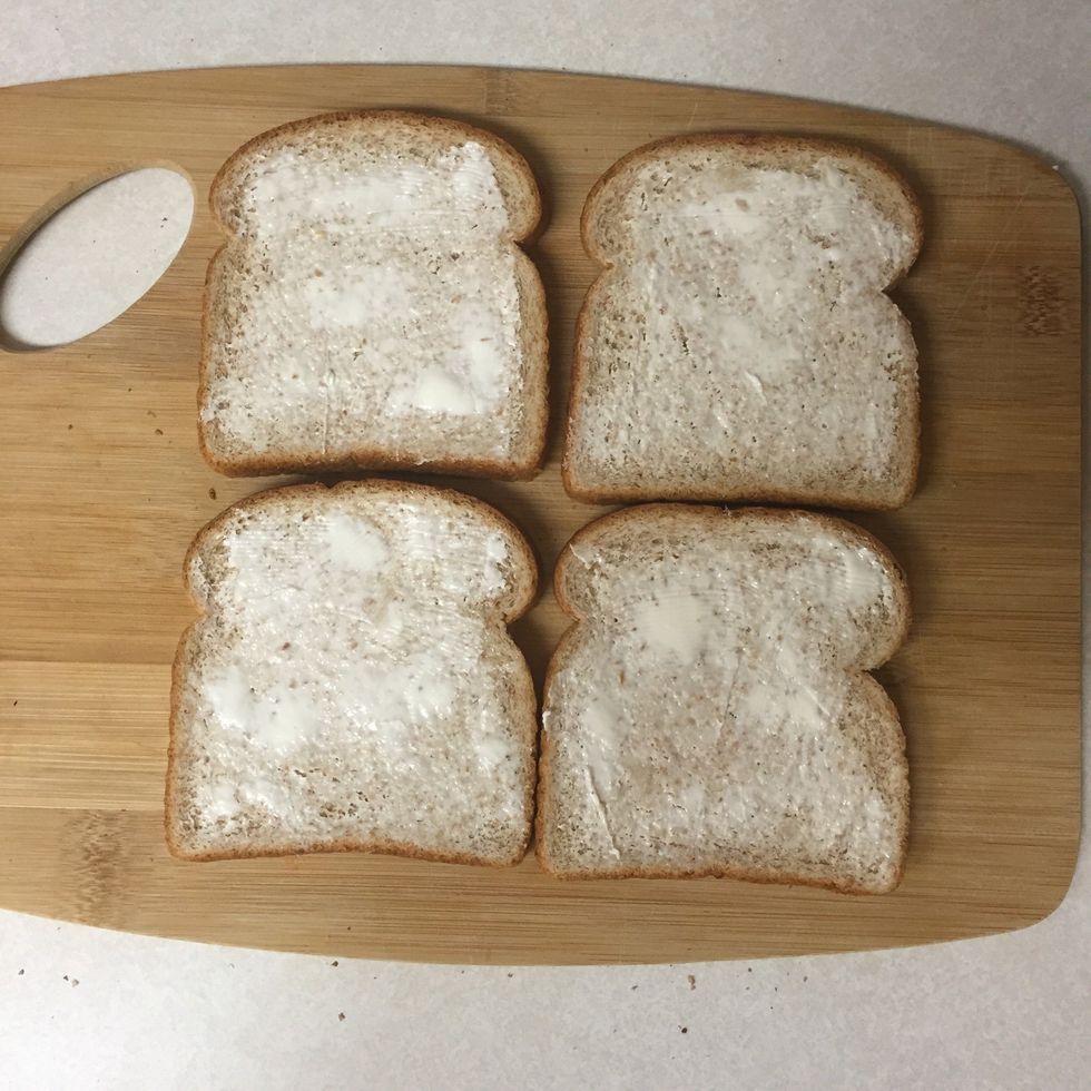 Prep your bread by buttering four slices (two slices per sandwich)