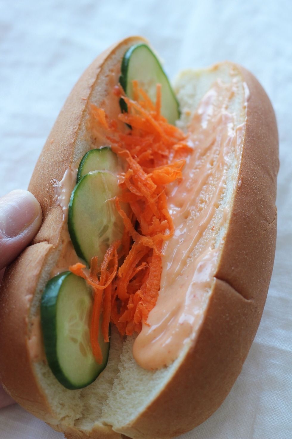 Prep your bun: Divide the spicy mayo among four buns, spreading down the side of each bun. Place slices of cucumber on each side and shredded carrots down the center of the bun.