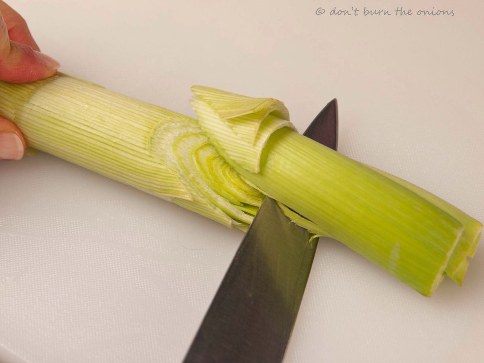 Prepare for washing by placing leek on chopping board and slicing the base diagonally on the two sides so that leek ends up with a peaked end. Doesn't have to be perfect!