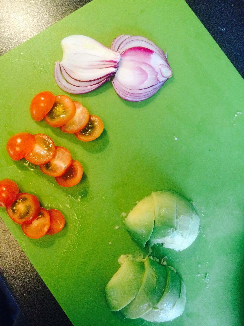Prepare the rest of the vegetables for the burger: avocado and tomatoes. Leave it on the chopping board together with the red onion.