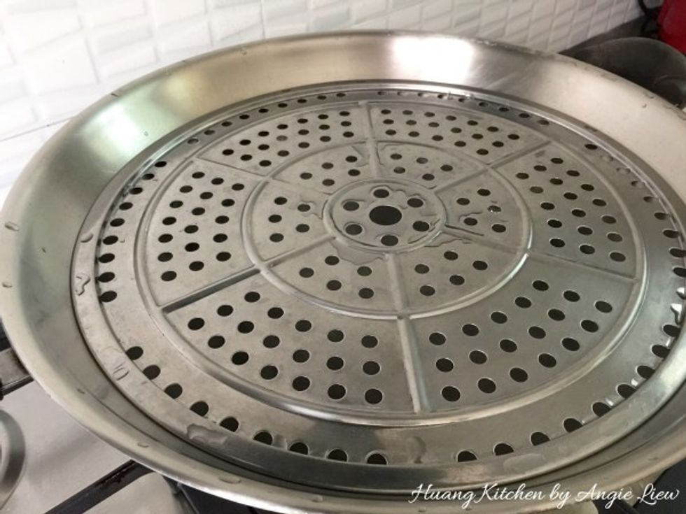 Prepare the steamer by boiling some water in a wok. Place a plate with holes to allow steam to pass in the wok.