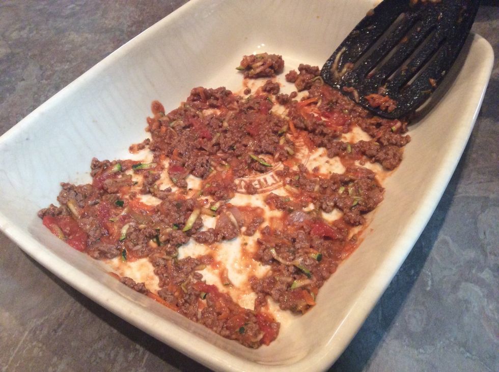 Prepare to layer the lasagna. Place thin covering of met on bottom of dish.