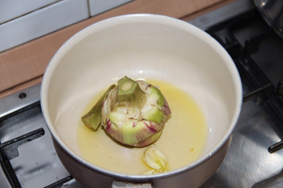 Prepare your artichoke. Please check how to make fried artichoke guide to see how to clean one. Put in pan with oilve oil and garlic