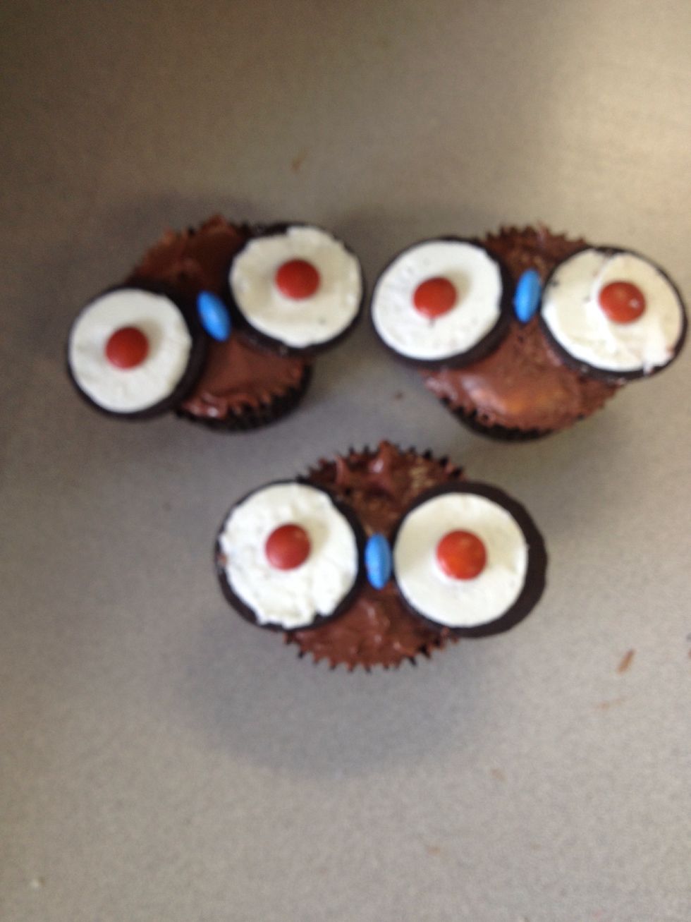 Press a MnM on its side into the centre of the cupcake between the two biscuits to act like a nose