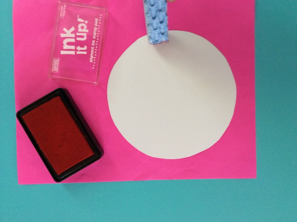 Press a sponge onto the rubber stamp pad, and stamp the edge of the large, white poster board circle.