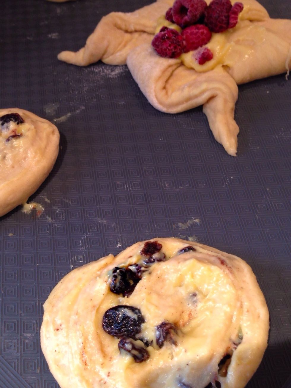 Press down slightly on the cinnamon swirls to flatten them a little. Add Creme Patissiere to the middle of the pinwheels and top with raspberries. Leave to prove for 1hr. Then brush with beaten egg